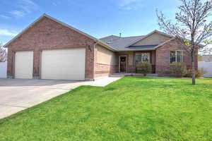 Rambler style home featuring a front yard, driveway, brick siding, and a garage