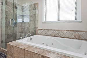Primary bath featuring a shower stall and a jetted tub