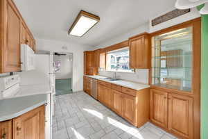 Kitchen featuring white microwave, light countertops, stainless steel dishwasher, a sink, and electric range oven