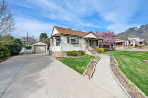 Bungalow-style house with driveway, a front yard, an outbuilding, a garage, and a tiled roof