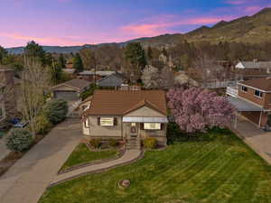 View of front of property featuring a front yard, a mountain view, a tile roof, and concrete driveway