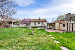 Rear view of house featuring a patio area, a storage shed, a yard, fence, and an outdoor structure