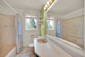 Full bathroom with toilet, shower / bath combo with shower curtain, tile patterned flooring, and vanity