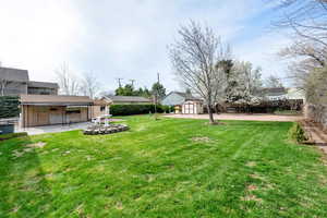 View of yard with an outbuilding, a patio area, a fenced backyard, and a storage unit