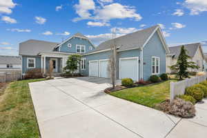 View of front of house featuring roof with shingles, fence, a front lawn, an attached garage, and driveway