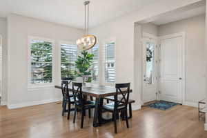 Dining area with light wood-style flooring, a chandelier, and baseboards