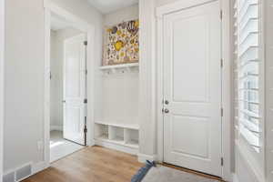 Mudroom featuring visible vents, baseboards, and wood finished floors