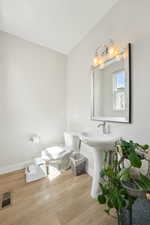 Half bathroom with toilet, wood finished floors, baseboards, and visible vents