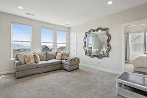 Carpeted living area with visible vents, baseboards, and recessed lighting