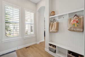 Mudroom with visible vents, baseboards, light wood finished floors, and arched walkways