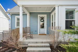 View of exterior entry with a porch and roof with shingles