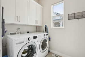 Laundry room featuring baseboards, light tile patterned floors, visible vents, washer and clothes dryer, and cabinet space