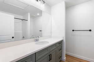 Full bathroom featuring baseboards, vanity, wood finished floors, and a shower