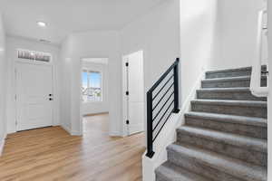 Entrance foyer with light wood finished floors, baseboards, visible vents, recessed lighting, and stairway