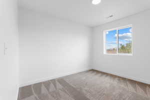 Empty room with carpet floors, visible vents, and baseboards