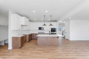Kitchen with light wood-type flooring, stainless steel appliances, baseboards, and recessed lighting