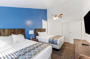 Carpeted bedroom with high vaulted ceiling and a ceiling fan