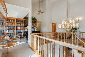 Hallway with high vaulted ceiling, an upstairs landing, and an inviting chandelier