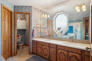 Full bath with a notable chandelier, a sink, and wallpapered walls