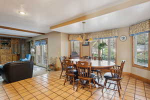 Dining room with light tile patterned floors, baseboards, a chandelier, and a textured ceiling