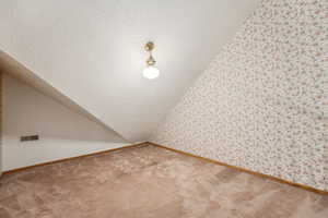 Bonus room with baseboards, vaulted ceiling, a textured ceiling, carpet floors, and visible vents