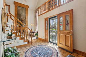 Entrance foyer with stairs, vaulted ceiling, wallpapered walls, and light tile patterned flooring