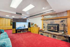 Cinema room with visible vents, a stone fireplace, and carpet floors
