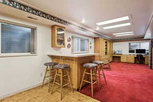 Kitchen with visible vents, glass insert cabinets, light countertops, a kitchen bar, and a peninsula