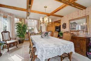 Dining area with a wealth of natural light, an inviting chandelier, coffered ceiling, and wallpapered walls