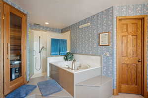 Bathroom featuring a bath, a textured ceiling, walk in shower, and wallpapered walls