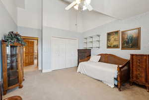 Carpeted bedroom with high vaulted ceiling, a closet, wallpapered walls, and ceiling fan