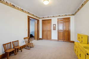 Living area featuring baseboards, a textured ceiling, and light colored carpet