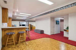 Kitchen with a peninsula, visible vents, a breakfast bar, open floor plan, and baseboards