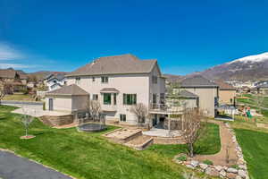 Back of house with a mountain view, a patio area, a trampoline, stucco siding, and a residential view