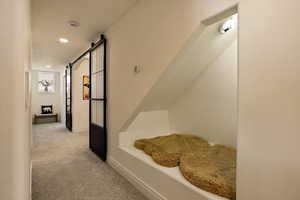 Hall featuring carpet flooring, baseboards, recessed lighting, and a barn door