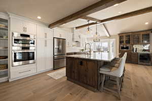 Kitchen featuring wine cooler, a sink, premium range hood, decorative backsplash, and appliances with stainless steel finishes