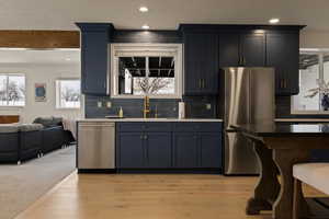 Kitchen with tasteful backsplash, light wood-style floors, a sink, and appliances with stainless steel finishes
