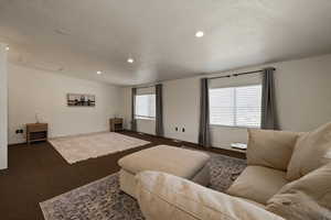 Living area featuring baseboards, recessed lighting, a textured ceiling, attic access, and dark carpet