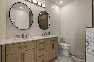 Full bath featuring double vanity, marble finish floor, a sink, and toilet