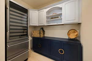 Kitchen with beverage cooler, open shelves, and white cabinets