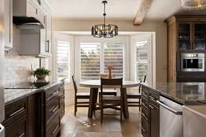 Interior space featuring plenty of natural light, beam ceiling, light wood-style flooring, and an inviting chandelier