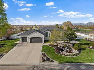 French country style house featuring an attached garage, driveway, a front yard, and stone siding