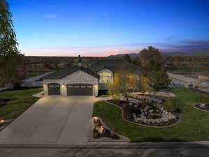 French provincial home with fence, stone siding, a front lawn, an attached garage, and concrete driveway