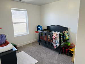 Carpeted bedroom featuring baseboards and visible vents