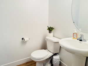 Half bath with toilet, wood finished floors, and baseboards