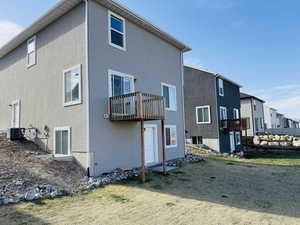 Rear view of house with stucco siding, central AC unit, and a balcony
