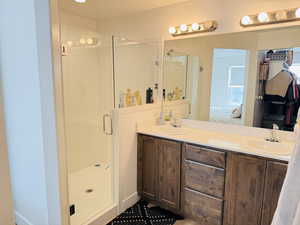 Bathroom with a sink, a shower stall, connected bathroom, and double vanity