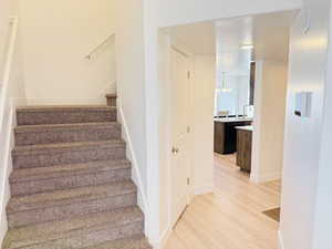 Stairway with wood finished floors and baseboards