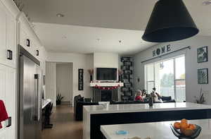 Kitchen featuring open floor plan, light countertops, dark wood finished floors, high end fridge, and white cabinetry