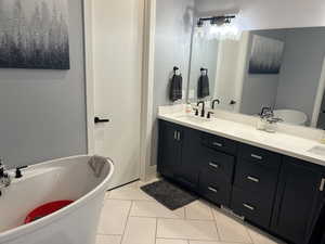 Bathroom featuring tile patterned flooring, double vanity, a sink, and a freestanding tub
